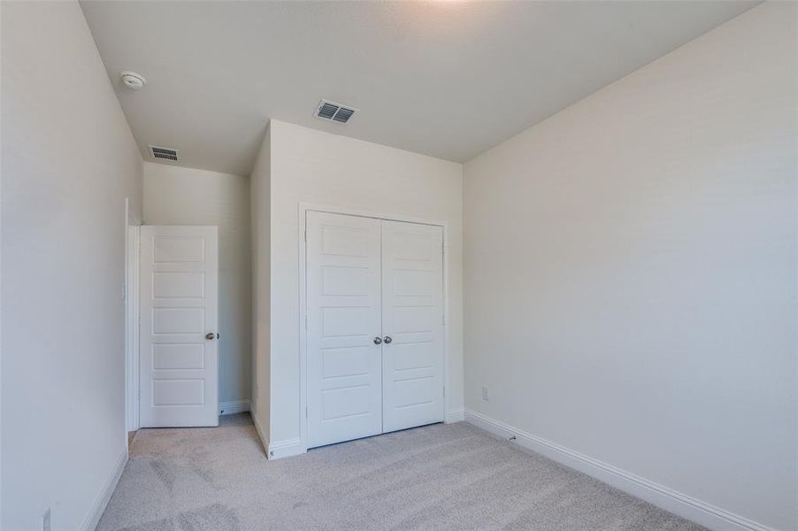 Unfurnished bedroom featuring light carpet and a closet