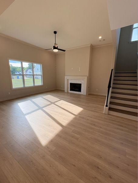 Spacious living area featuring wood-finish flooring, a contemporary ceiling fan, and a fireplace with a tile surround and white mantel