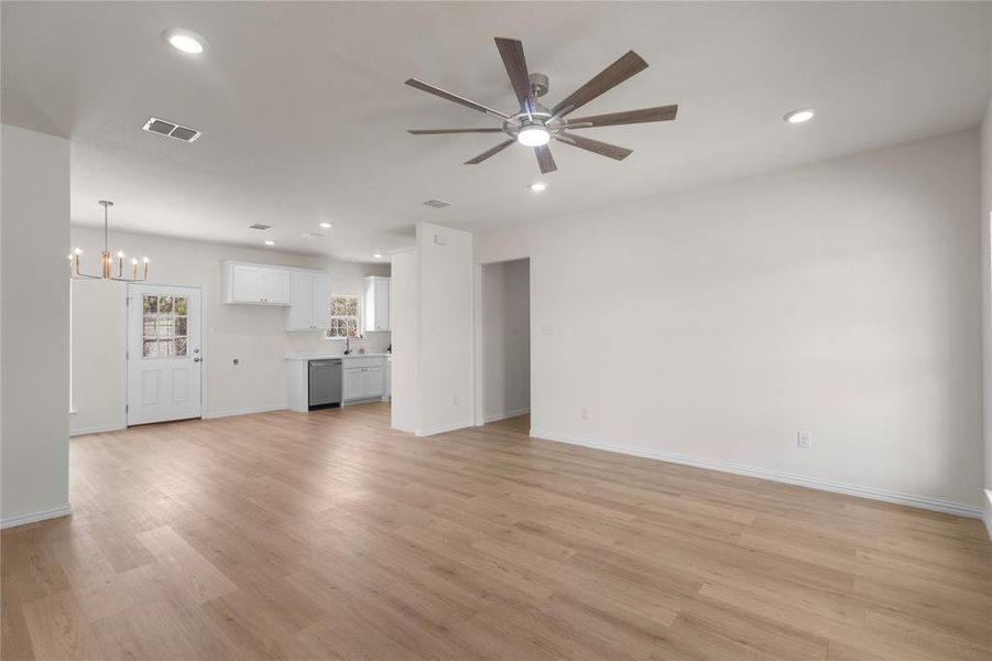 Unfurnished living room with light wood finished floors, recessed lighting, ceiling fan, and a chandelier