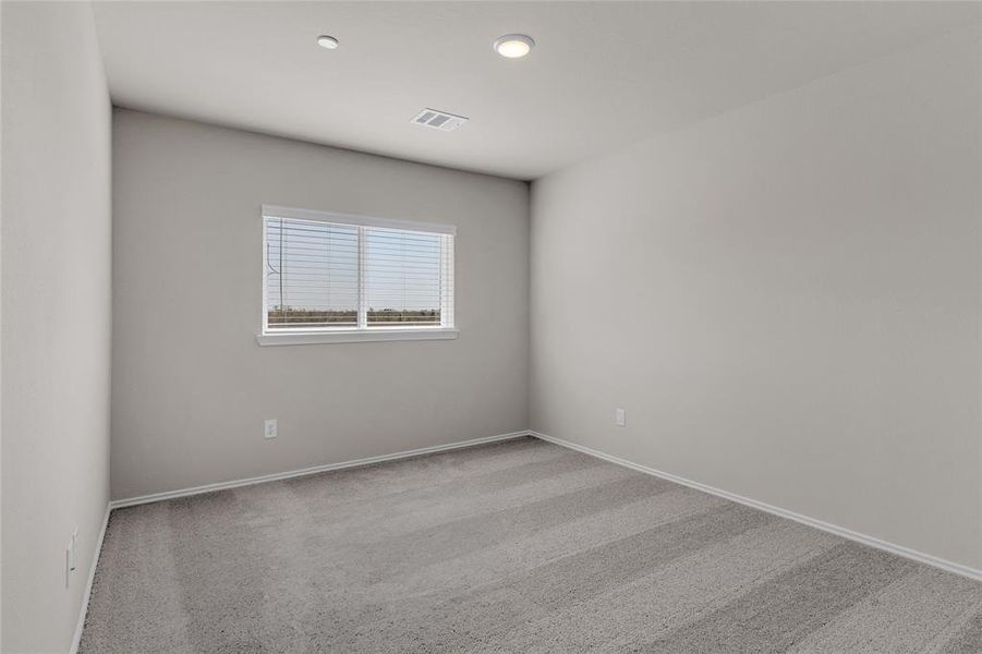 This is a bright 2nd bedroom, featuring neutral-colored walls and carpeted flooring, with a window allowing for natural light.