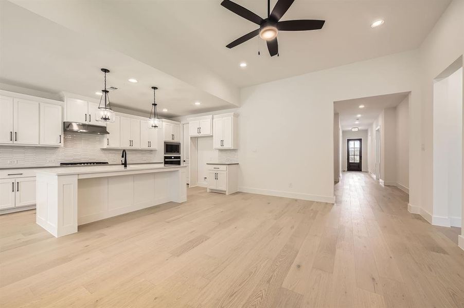Kitchen featuring under cabinet range hood, black oven, tasteful backsplash, a ceiling fan, and recessed lighting