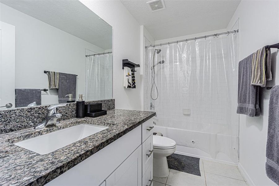 Bath 2 with tub/shower combo, granite countertop, and white shaker cabinet