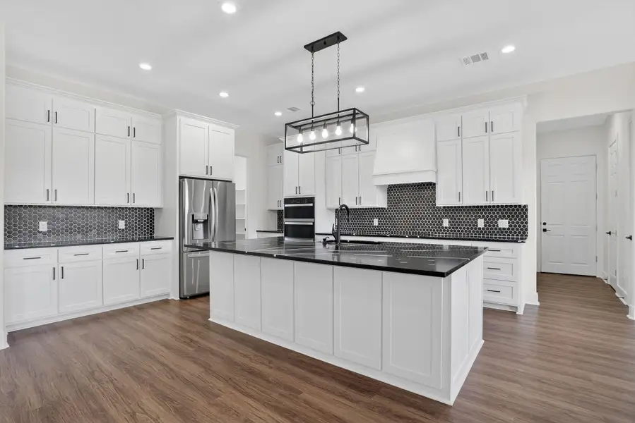 Kitchen featuring dark wood-style floors, stainless steel refrigerator with ice dispenser, white cabinetry, and recessed lighting Kitchen featuring dark wood-style floors, stainless steel refrigerator with ice dispenser, white cabinetry, and recessed lighting