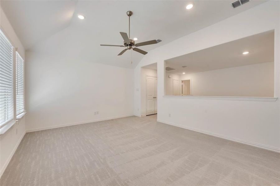 Unfurnished living room featuring light carpet, lofted ceiling, and ceiling fan