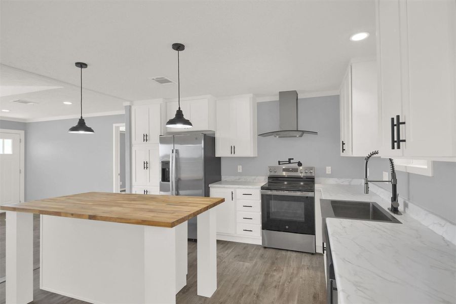 An open kitchen pairs custom countertops with clean shaker cabinetry and recessed lighting.
