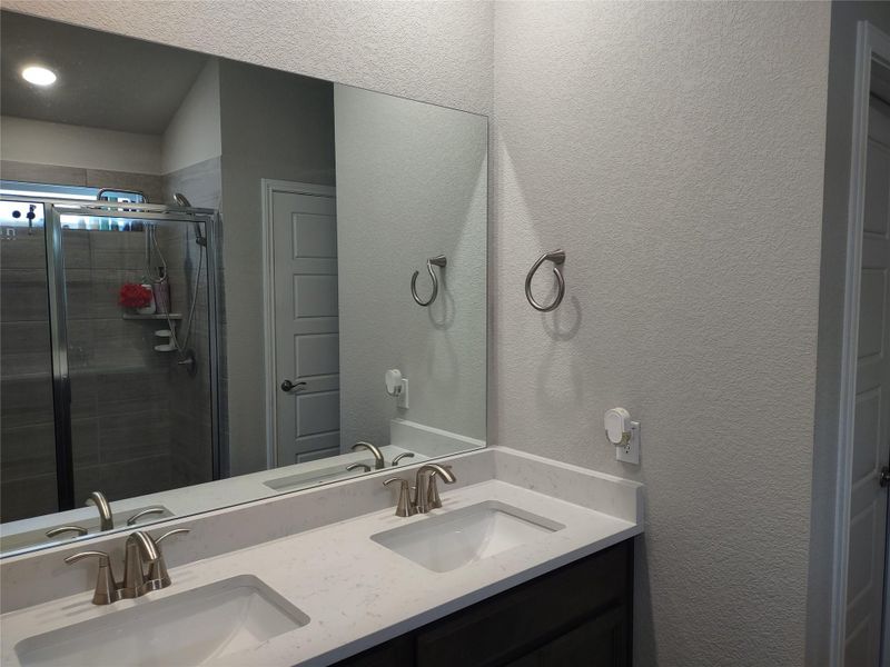 Bathroom featuring a stall shower, double vanity