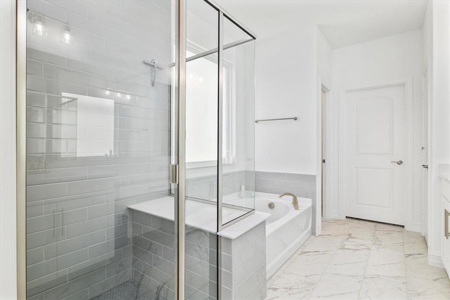 Spacious bathroom featuring a glass-enclosed shower with subway tile surround and built-in bench, a separate soaking tub with deck-mounted fixtures, and large format marble-look floor tiles