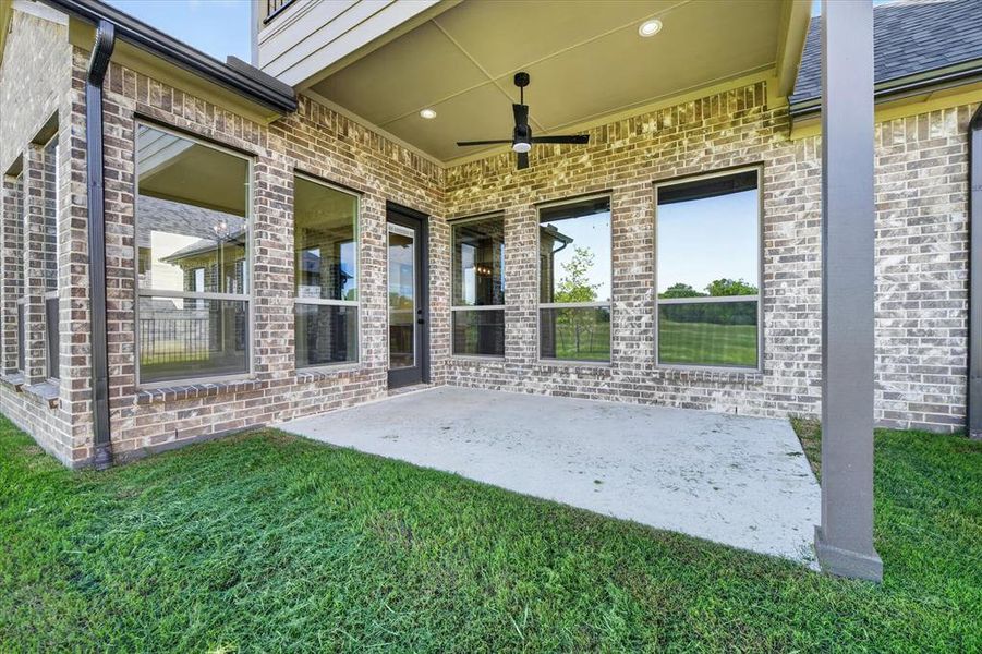 Covered patio with a ceiling fan and recessed lighting, featuring a brick exterior facade