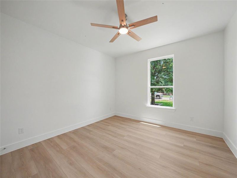 Bedroom featuring wood-finish flooring, white walls, and a contemporary ceiling fan with integrated lighting Bedroom featuring wood-finish flooring, white walls, and a contemporary ceiling fan with integrated lighting