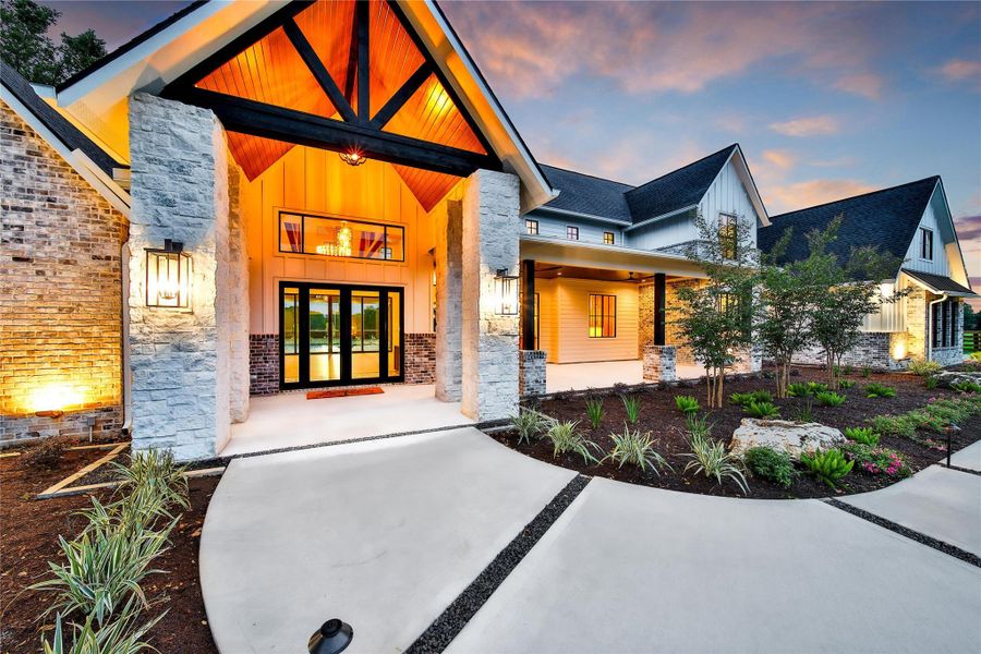 A sleek entry sets the tone to this warm and inviting front porch and covered patio.  Large glass doors and picture frame windows beckon you inside. Enhanced exterior light features guide guests along a beautifully landscaped path of concrete and black star rocks. An array of native plants add color and texture and modern drain techniques are used to ensure the area is well pampered.