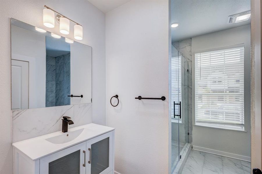 Bathroom featuring tile patterned floors, vanity, and an enclosed shower