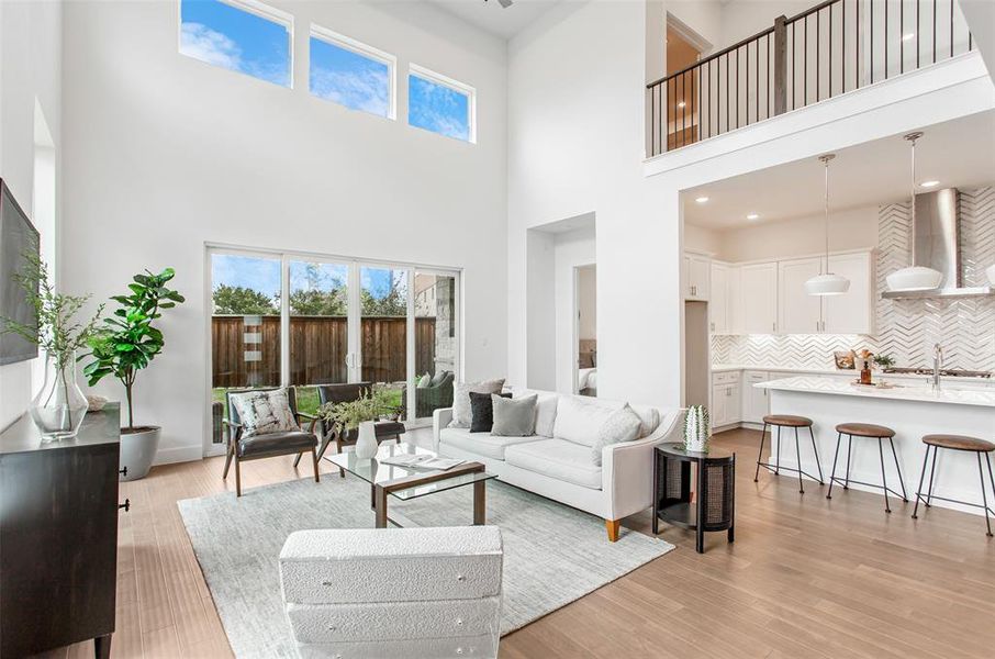 Living room with sink, light wood-type flooring, and a towering ceiling