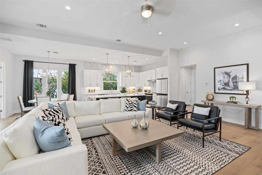 Living room featuring a chandelier, light wood-style flooring, a ceiling fan, and recessed lighting. The photos shown are of a completed home with the same floor plan and may not reflect the exact finishes, features, or layout of the home currently under construction.