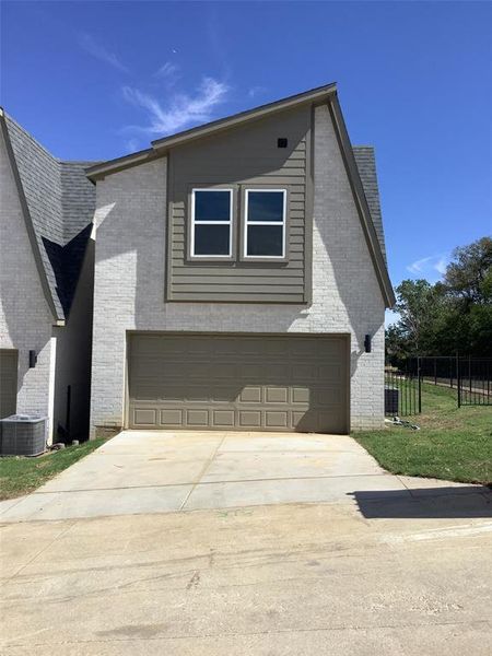 View of front of home with central AC unit and a garage