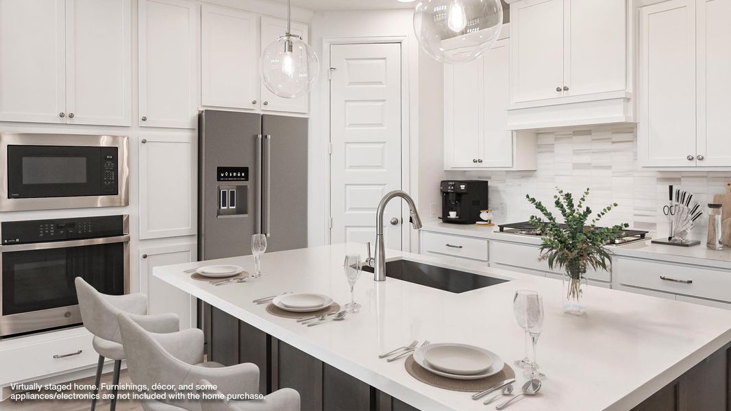 Kitchen with stainless steel appliances, a sink, a kitchen breakfast bar, white cabinets, and light countertops
