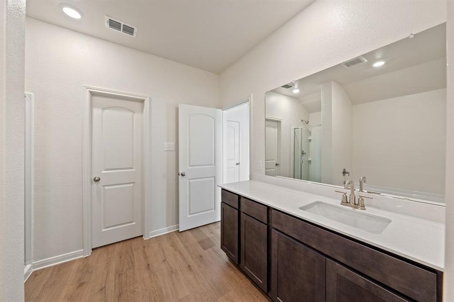 Bathroom featuring vanity, wood-style floors, vaulted ceiling, and a shower with shower door