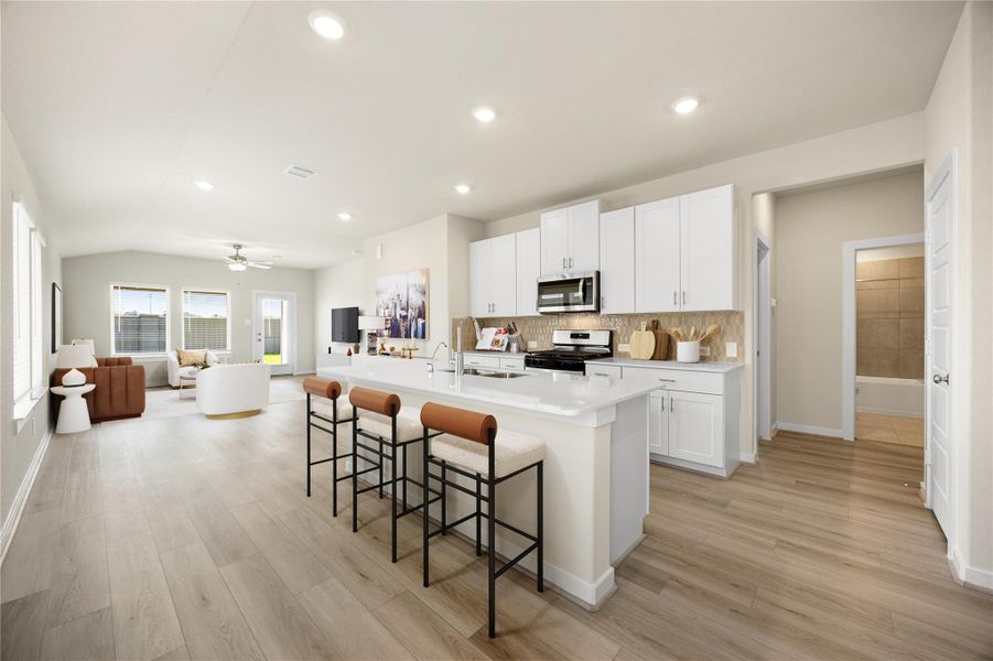 This Pinnacle's open-concept layout seamlessly connects the kitchen and living area, featuring bright finishes, stainless steel appliances, and a spacious island with bar seating, ideal for gatherings or quiet mornings at home.