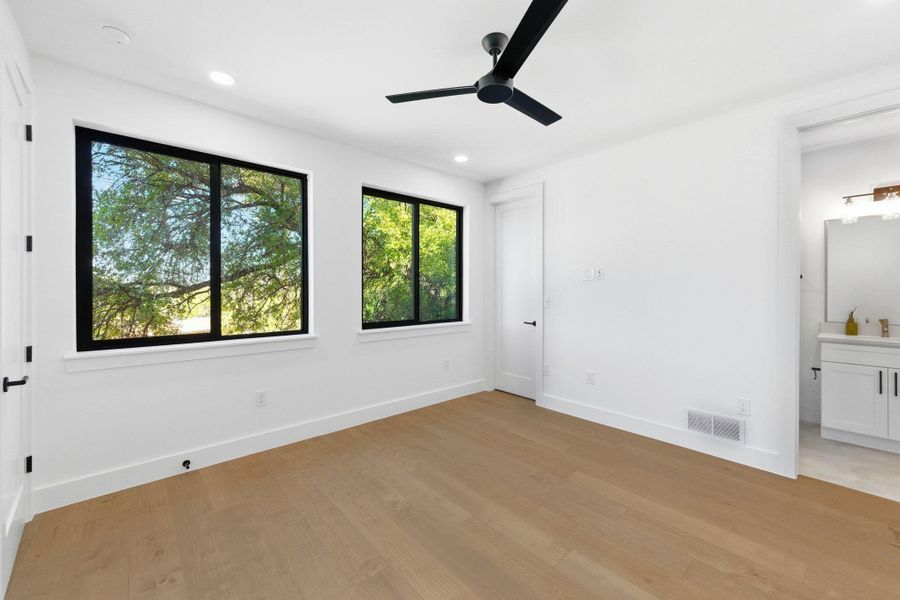 Ensuite bedroom with recessed lighting, ceiling fan, ensuite bath, and light wood finished floors plus lots of natural light