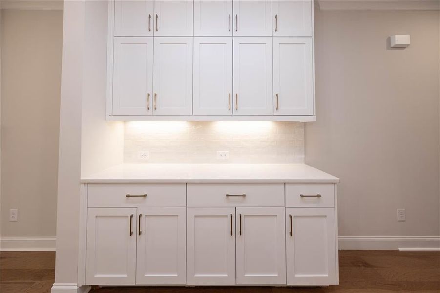 Detailed view of tasteful backsplash, crown molding, and wood finished floors