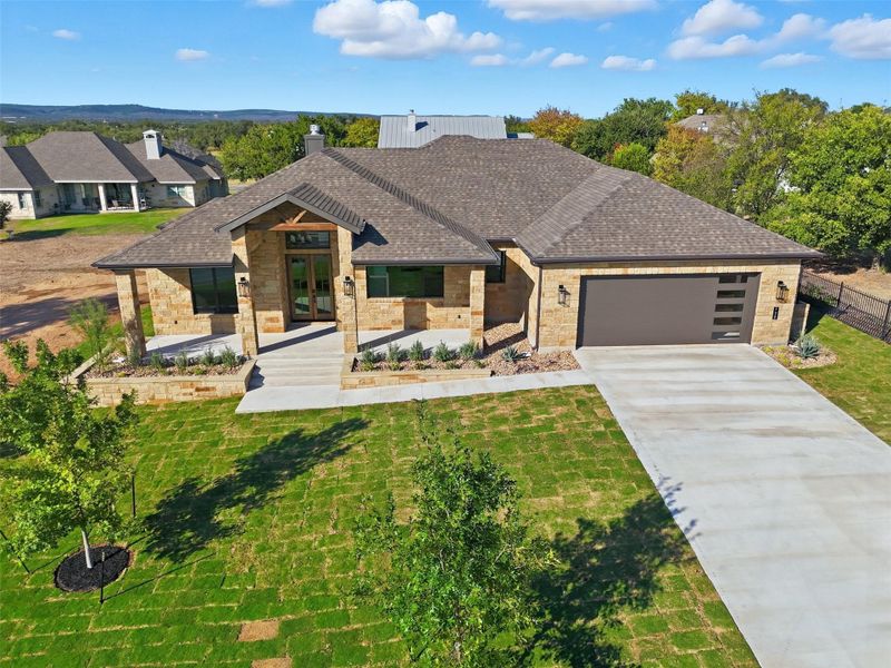 View of front facade featuring french doors, driveway, a shingled roof, a garage, and a front yard View of front facade featuring french doors, driveway, a shingled roof, a garage, and a front yard