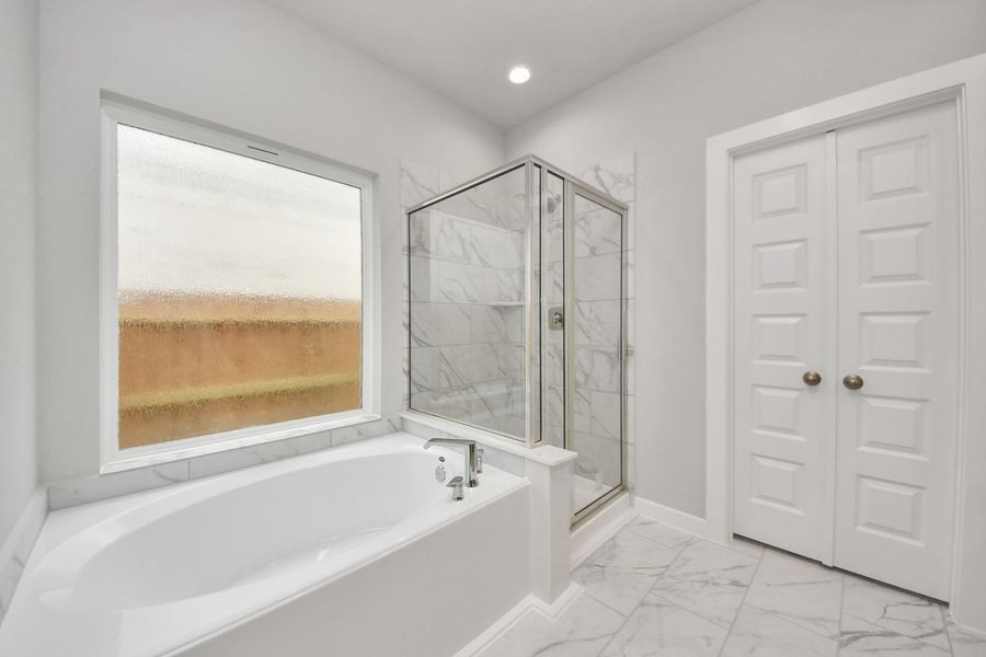 Delight in a spacious walk-in shower enveloped in stylish tile surround, and unwindin a separate garden tub adorned with custom detailing.