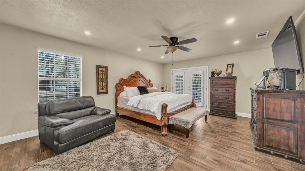 Bedroom with ceiling fan, access to outside, a textured ceiling, wood-type flooring, and french doors