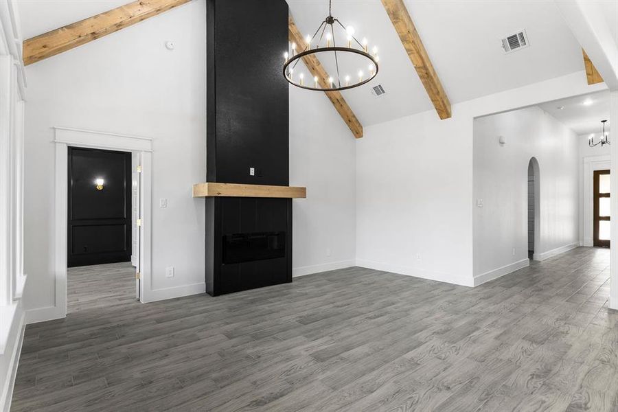 Unfurnished living room with a chandelier, beam ceiling, dark hardwood / wood-style flooring, and high vaulted ceiling