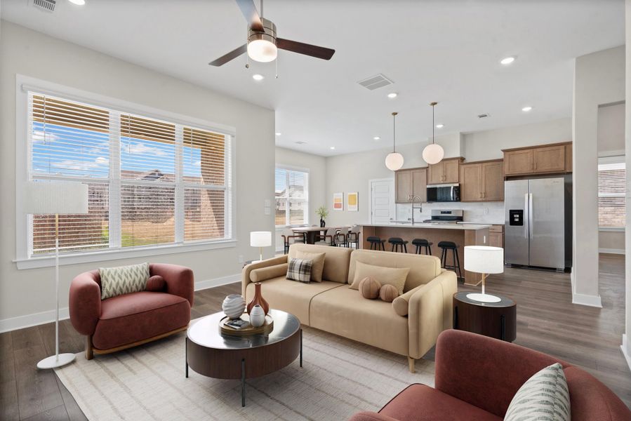 Open-concept living area featuring a ceiling fan, multiple windows, wood-finish flooring, and recessed lighting
