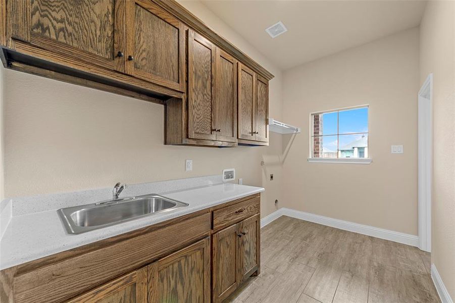 Laundry area with washer hookup, cabinet space, electric dryer hookup, baseboards, and light wood-style floors