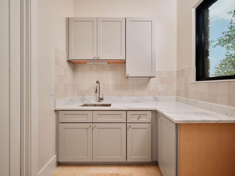 A well-appointed wet bar with ample counter space and storage cabinetry, illuminated by natural light. A well-appointed wet bar with ample counter space and storage cabinetry, illuminated by natural light.