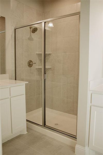 Bathroom with an enclosed shower, vanity, and tile patterned flooring