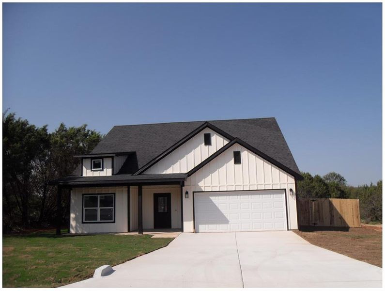 View of front facade featuring a front yard and a garage