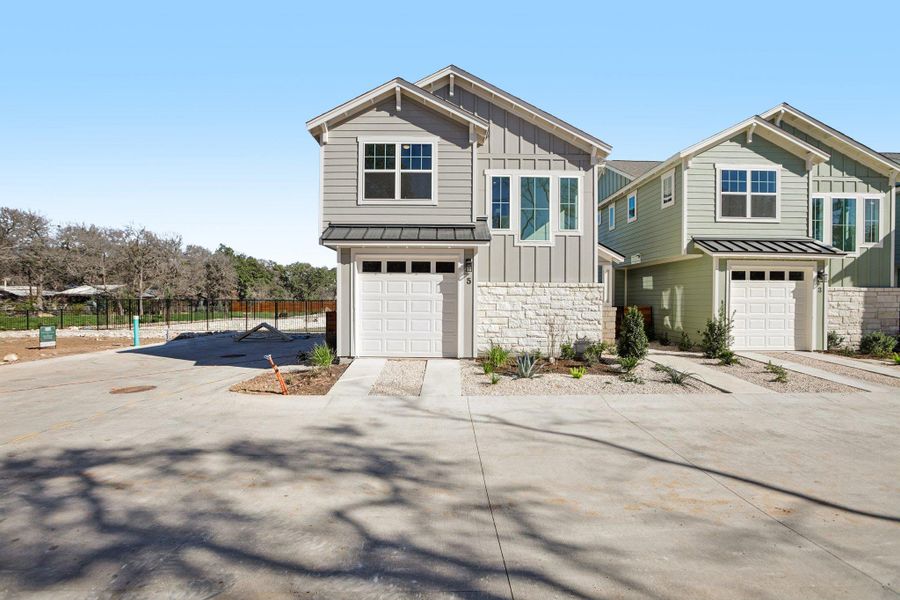 View of front of property with board and batten siding, stone siding, an attached garage, and driveway