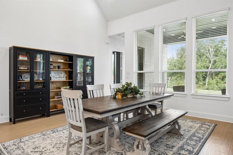 Dining area featuring a vaulted ceiling, wood-finish flooring, and multiple large windows providing abundant natural light Dining area featuring a vaulted ceiling, wood-finish flooring, and multiple large windows providing abundant natural light