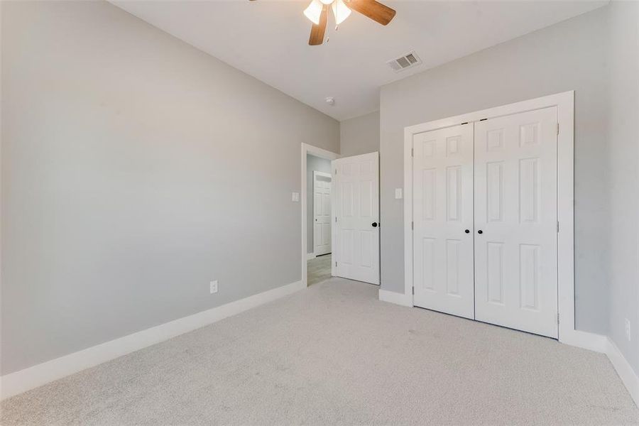 Unfurnished bedroom featuring light colored carpet, a closet, and ceiling fan