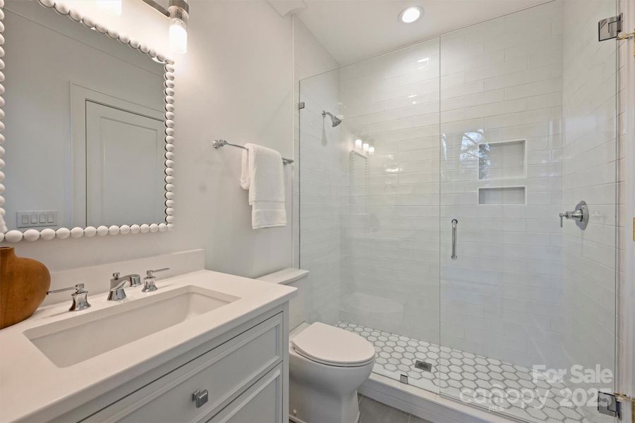 Ensuite bathroom to second bedroom, featuring quartz countertops and designer tile selections.