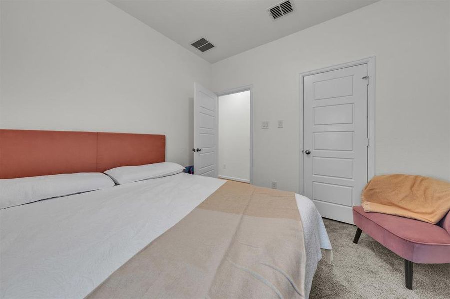 Bright room featuring light gray carpeting, white walls, and a five-panel interior door Bright room featuring light gray carpeting, white walls, and a five-panel interior door
