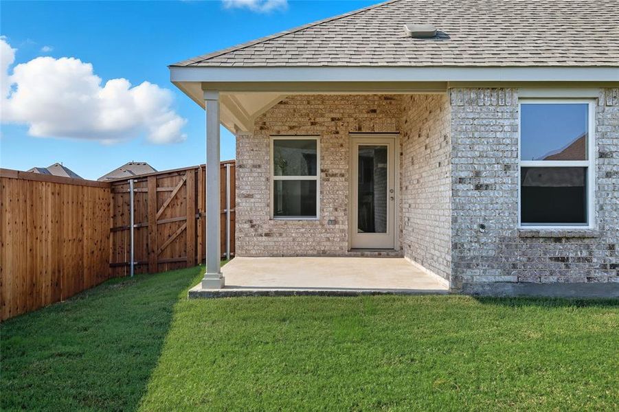 Doorway to property with a gate, roof with shingles, a patio, and brick siding Doorway to property with a gate, roof with shingles, a patio, and brick siding