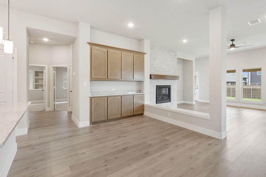 Open living area with wood-look floors, stone fireplace, and built-in wood cabinets