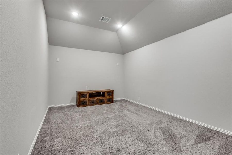 Carpeted spare room with vaulted ceiling