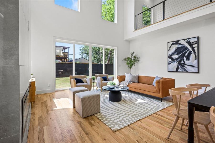 Living room with light hardwood / wood-style floors and a high ceiling