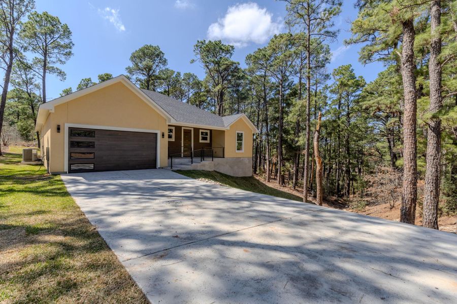View of front of home with an attached garage, driveway, and stucco siding