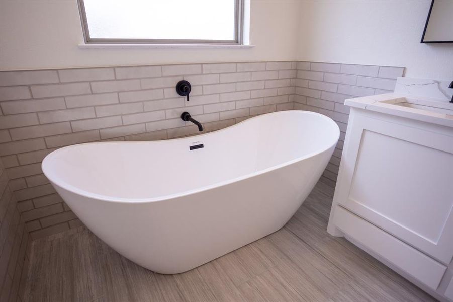 Bathroom with a freestanding bath, vanity, tile walls, and wainscoting Bathroom with a freestanding bath, vanity, tile walls, and wainscoting