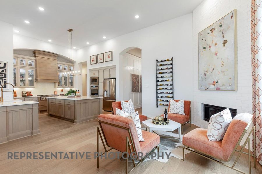 Living room with arched walkways, a glass covered fireplace, light wood-style floors, and recessed lighting