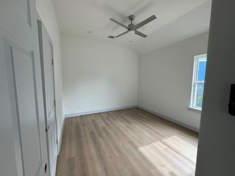 This is a bright, empty room with natural light, modern flooring, neutral walls, and a sleek ceiling fan. It appears to be move-in ready.