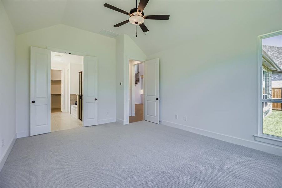 Unfurnished bedroom with lofted ceiling, light carpet, a ceiling fan, and connected bathroom