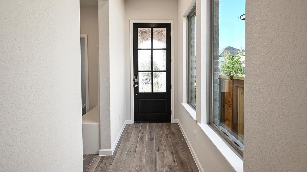 Doorway to outside with wood finish floors and a textured wall