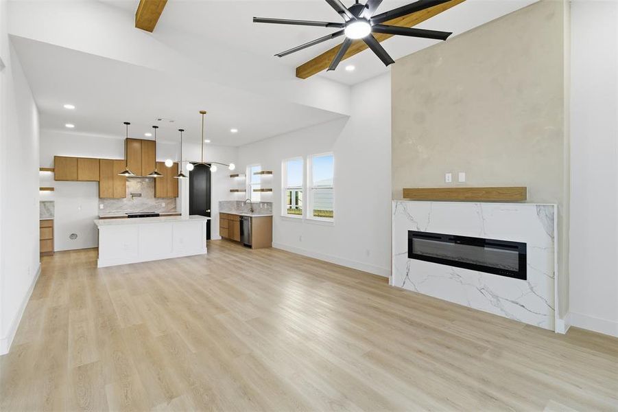 Unfurnished living room featuring ceiling fan, a premium fireplace, light wood-type flooring, and recessed lighting