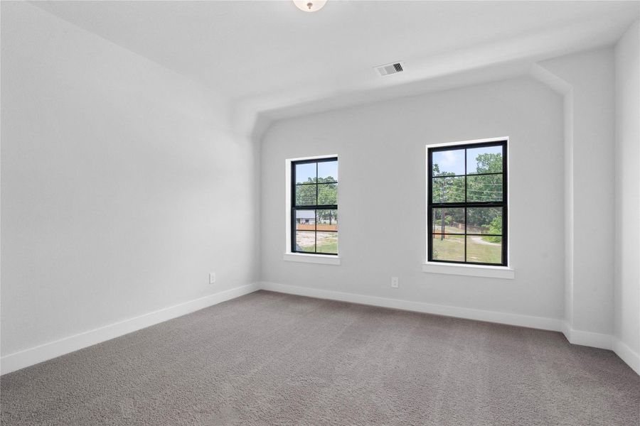 This cozy secondary bedroom offers plush soft carpeting, neutral walls ready for personalization, sun-filled windows, sloped ceilings, ample sized closet, and access to a private vanity and shared bathroom.