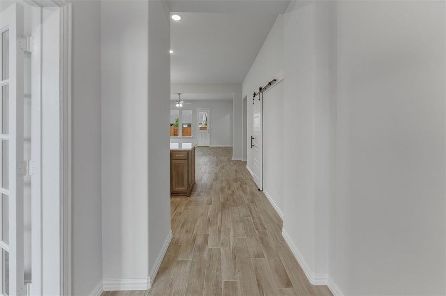 Hallway with wood-finish flooring, recessed lighting, and a white barn door